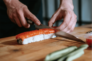 Detalhe de homem cortando sushi com faca