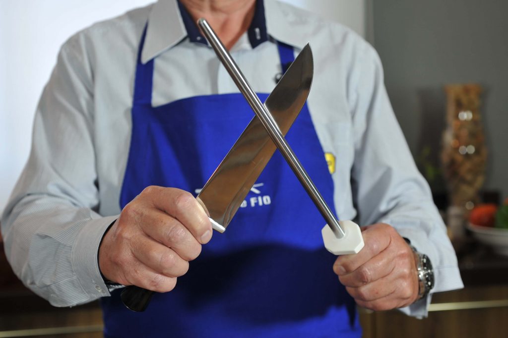 Homem demonstrando afiação de faca com chaira